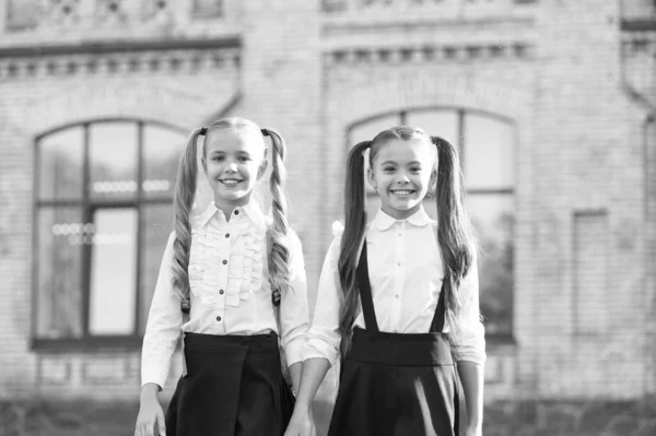 É uma sorte conhecer-nos. Alunas inteligentes e alegres. Boas alunas ao ar livre. Pequenas alunas usam uniforme escolar. Estudantes bonitos com rabo de cavalo longo olhar encantador. Fim do ano lectivo — Fotografia de Stock