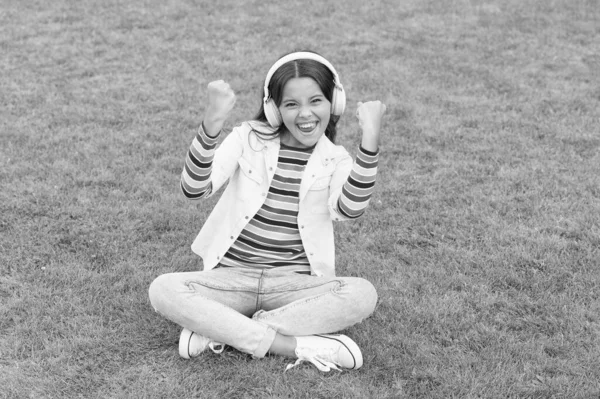 Zdrowy styl życia i relaks. Dziewczyna od jogi. Mały dzieciak w słuchawkach. Letnia playlista. cieszyć się wiosenną przyrodą. dziecko studiuje audiobook. nowej technologii. Dziecko słucha muzyki na zielonej trawie — Zdjęcie stockowe