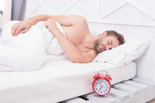 Sleeping clock round. Sleeping man in bed. Sexy guy sleep in sleeping room. Bed and bedding. Bedroom and home. Good night sleep. Nap time. Early morning. Late evening. Comfort and relaxation