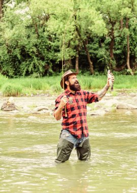 Trendy Hobby Store. bearded fisher in water. mature man fly fishing. man catching fish. fisherman show fishing technique use rod. summer weekend. Happy fly fishing. hobby and sport activity clipart