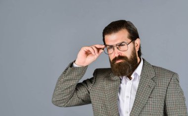 Resmi ofis hayatı. Ciddi sakallı adam. Pahalı takım elbiseli yakışıklı ve başarılı bir adam. O, beyaz gömlek ve gözlük takıyor. Takım elbiseli başarılı bir adam. İş adamı takım elbise giyer