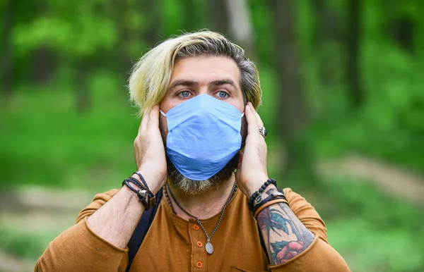 Hipster beschermt tegen luchtverontreiniging of coronavirus. Virusinfectie. De mens geniet van de natuur met gezichtsmasker. Vermijd infectie. Stop infectie. Kom langzaam uit de beperkingen van de vergrendeling. Wandelen in het park — Stockfoto