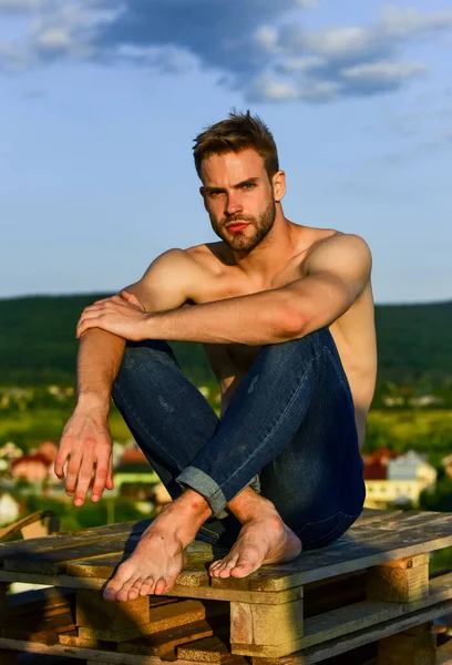 Sommer-Lookbook. Muskulöser nackter Oberkörper. Sixpacks muskulöse Brust. Mann im Freien blauer Himmel Hintergrund. Männliches Schönheitskonzept. Sportlich aussehende Machos tragen Jeanshosen. Muskelkräftiger Körper. Fitnessmodell — Stockfoto