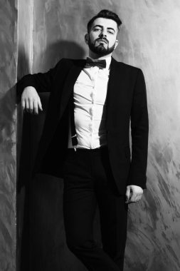 Stüdyo duvarında ciddi bir yüzü olan sakallı bir adam.