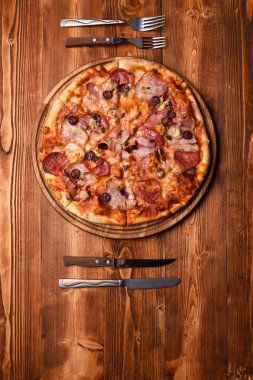 Pastırmalı pizza ve ahşap arka planda peynir.