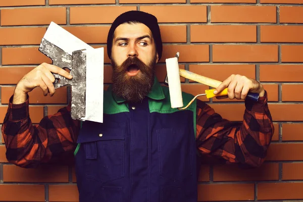 Бородатий майстер тримає різні будівельні інструменти з задоволеним обличчям — стокове фото