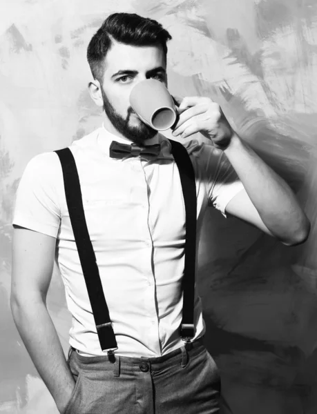 bearded man drinking tea or coffee with serious face