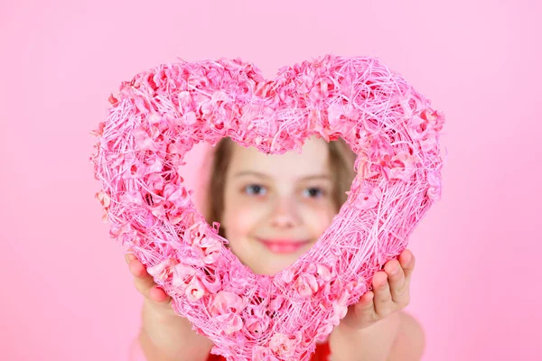 Chica feliz mirando a través del corazón rosado sobre fondo rosa — Foto de Stock