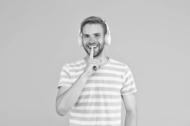Müzikte sessizlik sesten daha önemlidir. Mutlu adam gizli jest yapar. Adam kulaklıkla müzik dinliyor. Ses ve müzik teknolojisi. Stereo sesi. Müzik çalarken sessizlik lütfen.