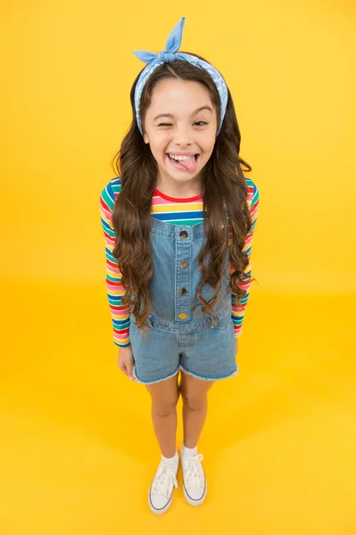 Fun lifestyle little girl long hair denim overalls, cheerful grimace concept — Stock Photo, Image