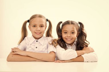 Birinci sınıf. Liseli kızlar masa başı beyaz arka planda otururlar. Liseli kızlar duygusal arkadaşlar. Mutlu bir çocukluk. Sevimli liseli kızlar. Okula dönelim. Eğitim konsepti. Güzel kızlar en iyi arkadaşlar. Resmi biçim