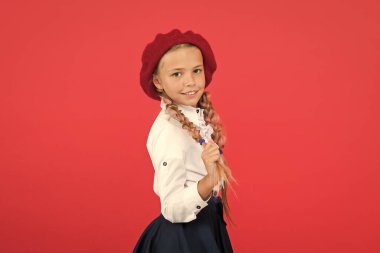 Süslü bir tarz. Saçları örgülü küçük kız okula gitmeye hazır. Fransızca konuşabiliyor musun? Okul moda konsepti. Liseli kız resmi okul üniforması ve bere takıyor. Çocuk güzel kız uzun örgülü saçlar