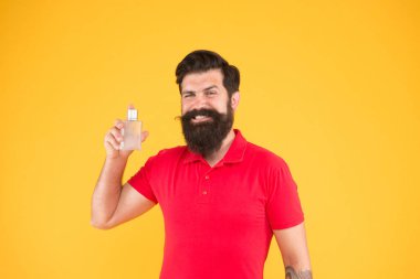 Sakallı adam parfüm şişesi tutuyor. Gerçek erkekler için mükemmel bir koku. Vahşi hippiler kokuyu seçer. Olgun bir adam deodorant önerdi. Moda kolonya şişesi. Hijyen ve sağlık. tazeleniyor