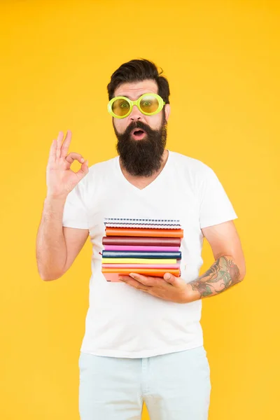 Buch-Nerd empfiehlt. Lesefreak zeigt Handbewegung. Geek Student gelben Hintergrund. Ein bärtiger Mann mit Brille hält Bücher in der Hand. Bücher, die man unbedingt lesen muss. Schulbibliothek. Lesen und Wissen — Stockfoto