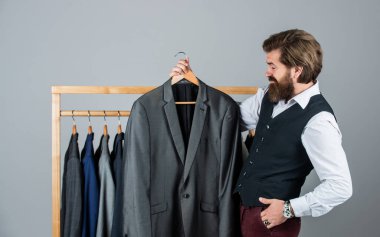 Müşterilerle temas halinde. Kendine güvenen terzi erkek ceketi tasarlıyor. Mezura takan yakışıklı bir sartor. Erkek güzellik ve moda. Sakallı adam, terzi kıyafetleri. Resmi ve ofis kıyafetleri. İş adamı