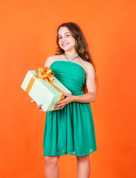 Niña sonriente con un regalo de compras. Venta Viernes Negro. concepto de vacaciones. Día internacional de los niños. Alegre niña sosteniendo caja envuelta en regalo. Tenencia de regalo en la mano — Foto de Stock