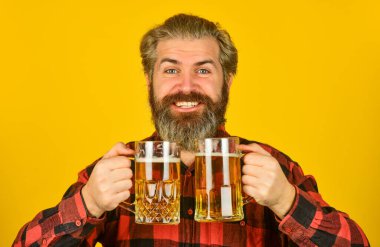 Yaşam tarzı konsepti. Vahşi hippi bira içer. Olgun sakallı barmen elinde bira bardağı tutuyor. Kendine güvenen barmen kadeh kaldırıyor. Boş zaman ve kutlama. Bar 'da bira içen bir adam. Köpüklü bira.