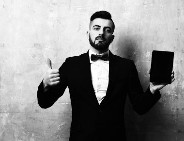 Sakallı bir iş adamı tablet tutuyor ve başparmağını kaldırıyor.