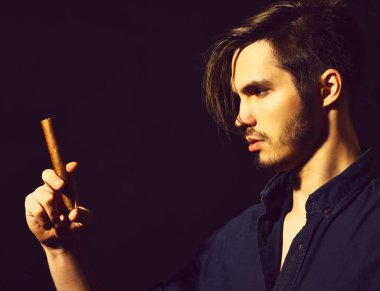 Sigara içen ciddi sakallı bir adam.