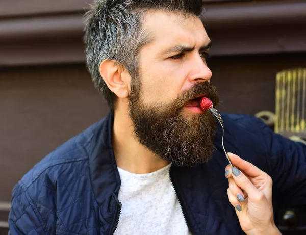 ひげを生やした男性は背景にラズベリーを食べる. — ストック写真