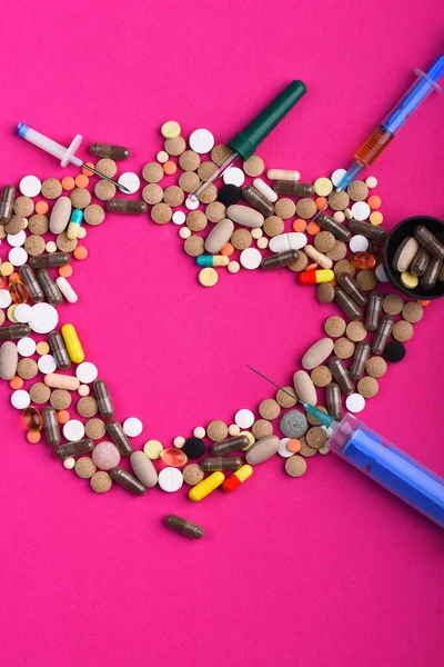 Sada barevných pilulek roztroušených na růžovém pozadí — Stock fotografie