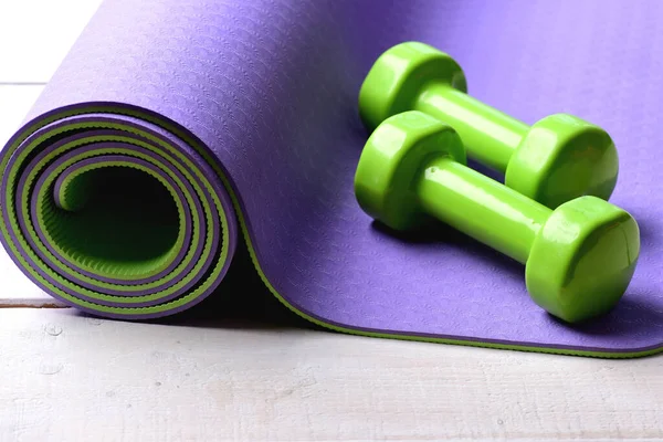 Shaping and fitness equipment. Barbells lying on purple yoga mat.