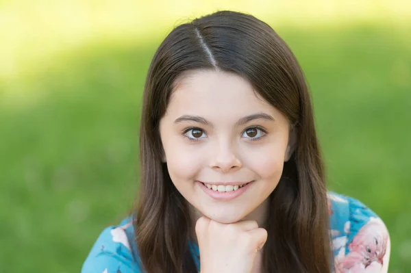 Menina com cabelos longos relaxante no parque ensolarado dia verde grama fundo, conceito sorriso adorável — Fotografia de Stock