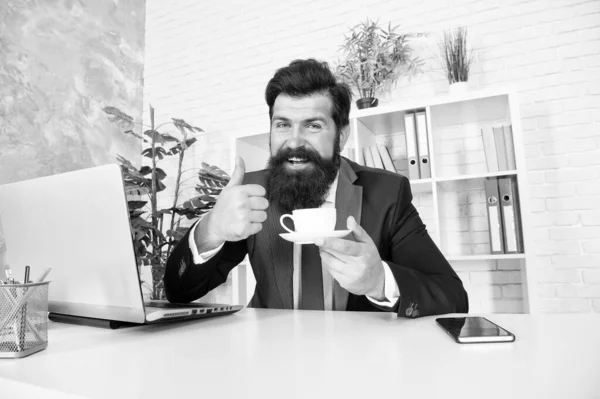Nejlepší čaj. Realitní makléř zvedne palec s šálkem čaje. Právník pije čaj v kanceláři. Vousáč si užívá přestávku na čaj na pracovišti. Kancelářský život. Práce přes den. Odpočinek v práci. Ráno a snídaně — Stock fotografie