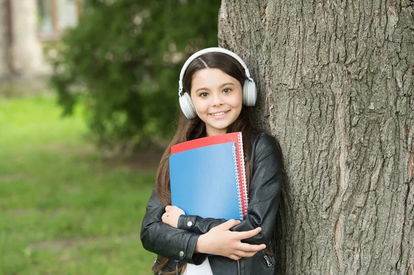 Menina ouvir áudio transportar livros didáticos relaxante parque de fundo, som em sua cabeça conceito — Fotografia de Stock