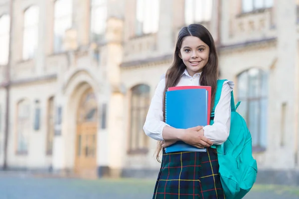 Klein meisje student school uniform en rugzak houden boeken, kennisdag concept — Stockfoto