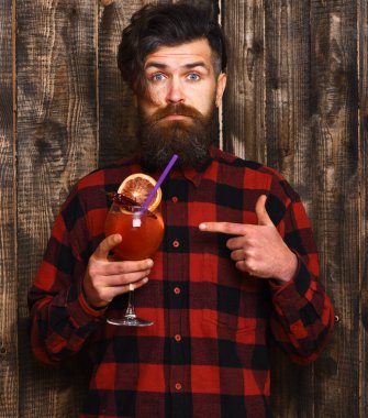 Çılgın parti, baharatlı, eğlenceli konsept. Sakallı adam tahta arka planda kokteylde parmağıyla işaret ediyor..