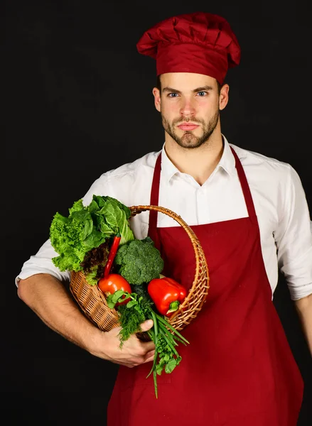 Koch mit neugieriger Miene hält Gemüse im Korb. — Stockfoto