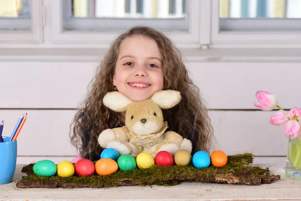 Chica feliz con juguete de conejo, lápiz, flores de tulipán, huevos de Pascua — Foto de Stock