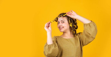 çocukluk mutluluğu. Kuaförde oynayan, saç bigudili mutlu kız. Çocuklar için saç stili yapmak için kolay ipuçları. Kuaför aletleri ve saç aksesuarları. Çocuk saç bigudileriyle poz veriyor.