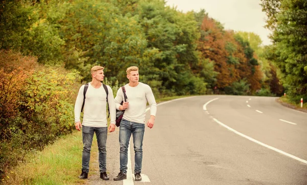 Need to go. wanderlust concept. Hiking with friends is cool. gone to find themselves. Travel hitch-hiking. twins walking along road. hitch hiking on empty road. travelling by hitchhiking. road trip