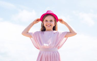 Flörtöz hissediyorum. Mutlu çocukluk. Küçük kızın uzun gür saçları var. Elbiseli çocuk. Kadın kuaför salonu. Güzellik ve yaz modası. Gökyüzü arka planındaki neşeli çocuk. Modayı takip eden çocuk.