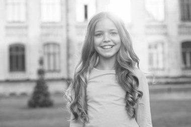 Yıldız gibi parla. Dışarıdaki mutlu kız. Tatlı gülüşlü bir kız çocuğu. Uzun kıvırcık saçlı küçük bir kız. Sıradan tarzda küçük bir kız. Güzellik ve kuaför salonu. Moda ve tarz. Çocukluk ve kızlık