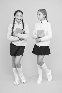 Geleceği oku. Sevimli küçük çocuklar kütüphaneden okumak için sarı arka planda kitaplar aldılar. Okumayı okulda öğrenen sevimli küçük kızlar. Okuyabiliriz.