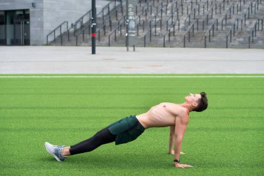 Sporcu Adam Kalas Egzersizi Yapıyor. Adam ters tahta egzersizi yapıyor. Yoga fitness adamı vücudunu tahta duruşuyla geriyor. Parkın çimlerinde ters planking egzersizi yapıyor. toplam vücut gücü