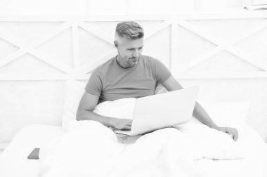 Yakışıklı adam dizüstü bilgisayarla iletişim kuruyor. Uyumadan önce defter kullan. Erkek blogcu internet teknolojisi kullanıyor. Bilgisayarda ağ kurmak. Evden bağımsız olarak çalışıyor. Karantina sırasında uzak görev