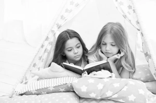 Lockdown ideas for kids. Keep studying at home. Favorite fairy tale. Book about love. Girls children lay bed read book. Pleasant time in cozy bedroom. Girls sisters cute pajamas relax and read book