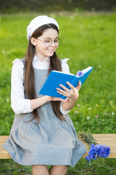 Елегантна школярка дівчинка читає книгу в парку, концепція французької мови — стокове фото