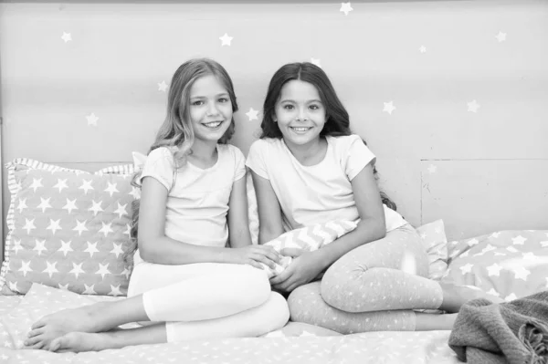 Altijd leuk. Gelukkige meisjes zitten op bed. Schoonheid van kleine meisjes. Kleine meisjes dragen huiskleding. Internationale dag van het meisje kind. Mooi wij. — Stockfoto