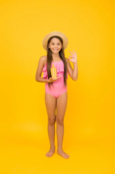 Menina pequena em maiô segurar protetor solar cosméticos creme, protegendo conceito de pele — Fotografia de Stock