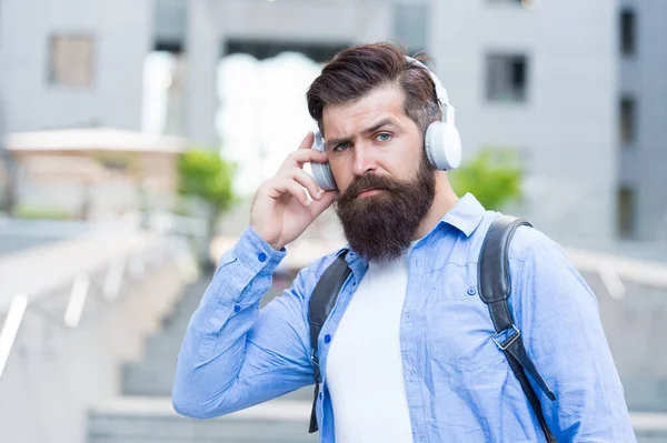 Live life loud with headphones. Hipster wear headphones outdoors. Bearded man listen to music in headphones. New technology. Modern life. Headphones for listening closely