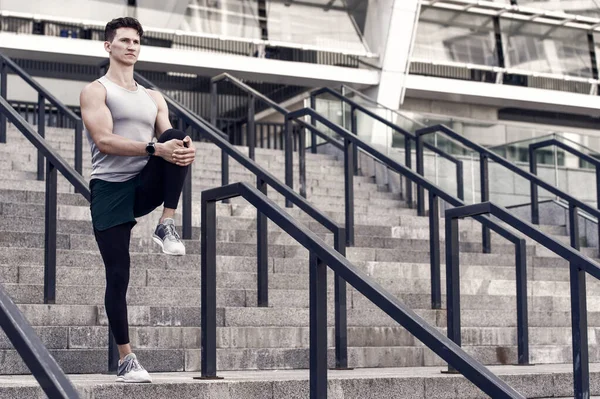 Retrato de un deportista atlético en ropa deportiva para correr. joven corredor de fitness hombre estirando las piernas antes de trotar. Calienta primero. vida sana y concepto de autocontrol. Hombre estiramiento — Foto de Stock