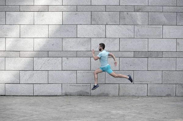 man running outdoor. Healthy male runner. hurry up. Full length portrait of fitness guy running. Achievement of success and excellence. Athlete running against concrete wall. Sport man starts to run
