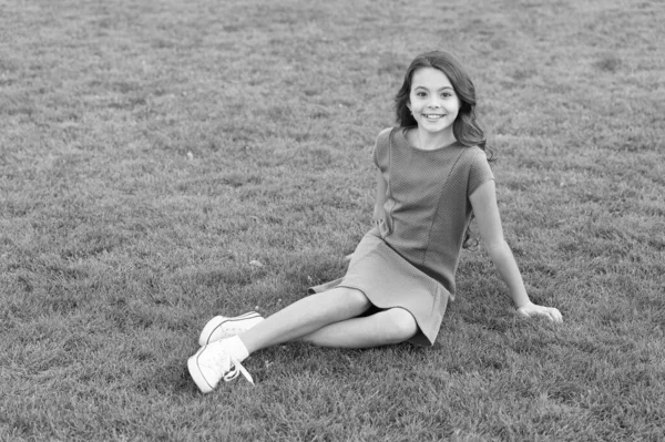 Grüner Sommer. Kleines Kind sitzt auf grünem Gras. Kleine Mädchen genießen den Sommertag. Frohe Sommerferien. Modische Sommertrends. Kinderkleidung — Stockfoto