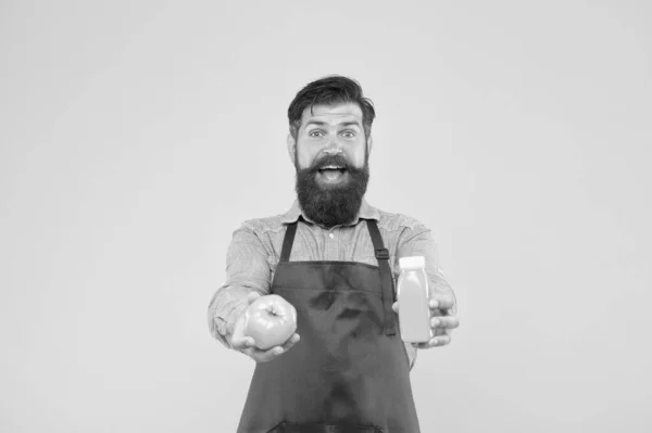 Homem barbudo chef segurar orgânico natural tomate e garrafa de fundo amarelo. Nutrição vegetariana. Bebida de batido. Sumo fresco. A espremer batido. Entregar vitaminas frescas. Bebida de batido Hipster — Fotografia de Stock