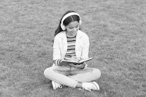 Online inlärning. Pedagogisk podcast. Gör det hända. Lyssna på musik utomhus. Coola tjejhörlurar som lyssnar. Ung flicka njuta av musik sitta äng. Trevligt att träffas. Barnhörlurar lyssna musik — Stockfoto